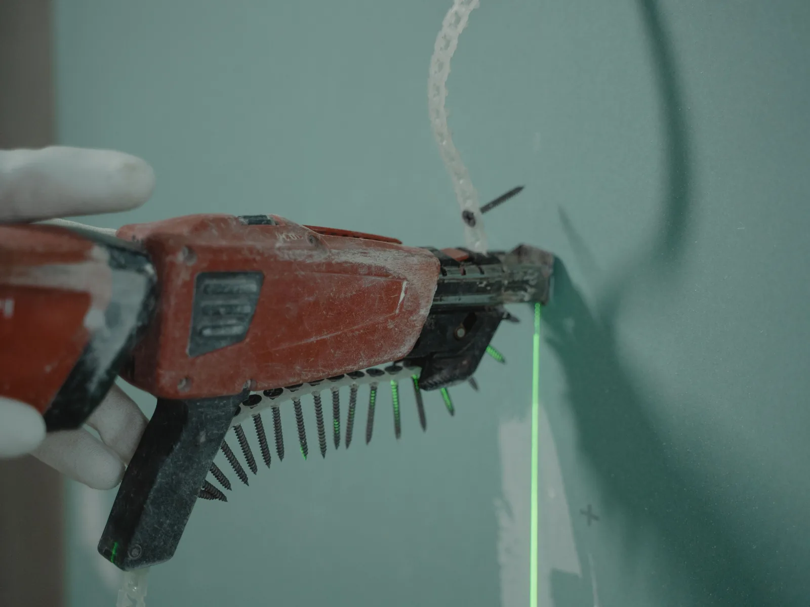 A screw gun driving into board, with a laser line marking the run